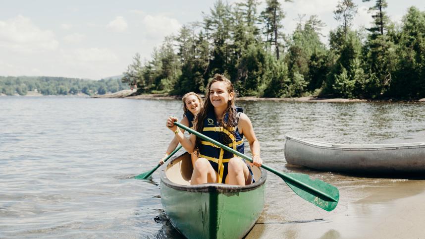 Two teenage girls paddling a canoe